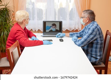 Video Communication Via The Internet Between Older Parents And Children. Old People In Masks And Gloves Are Looking At Measuring The Temperature On The Monitor. Home Quarantine. Coronavirus Pandemic.