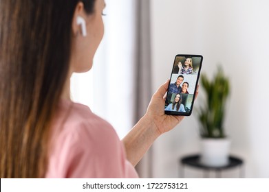 Video Communication Via Smartphone. A Young Woman Is Using Phone App For Video Call, Online Meeting. She Talks With A Several People Together In Same Time. Close-up Back View