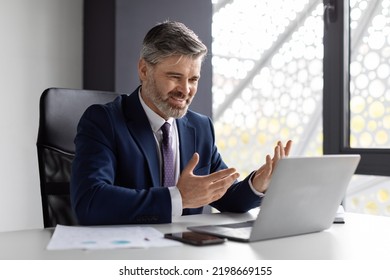 Video Conference. Handsome Middle Aged Businessman Having Web Call With Client, Smiling Male Entrepreneur In Suit Using Laptop For Online Communication, Talking And Gesturing At Camera, Free Space