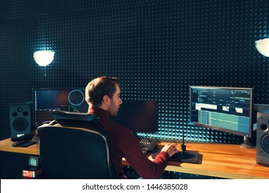 Video Editing. Professional Editor Adding Special Sound Effects. Back View Of Young Man Watching Graphs On Monitors. Copy Space On Gray Wall