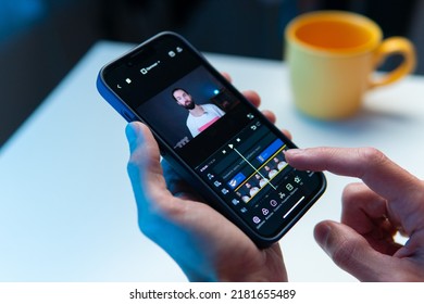 the video editor program on the phone. A young man is editing a video on his phone - Shutterstock ID 2181655489