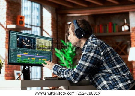Video editor selecting key frames to use while doing video montage, working from home on computer before deadline. Man using mouse to edit movie project footage in apartment office