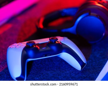 Video Game Accessories - Gamepad And Headphones On A Technological Background. Neon Lighting. There Are No People In The Photo. Video Games, Electronics, Modern Equipment,.