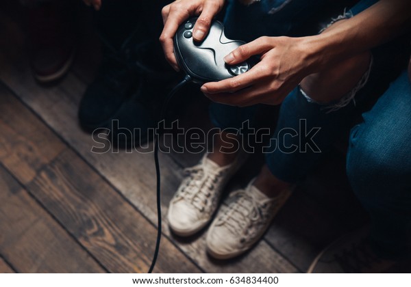 Video game addiction, psychological\
disorder excessive play, everyday unhealthy lifestyle. Closeup view\
of unrecognizable person hands with\
joystick.