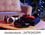 Video game console, wireless controller and headphones on wooden table indoors