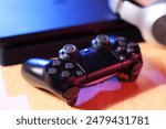 Video game console and wireless controller on wooden table, closeup