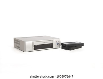Video player next to some video tapes. Silver colored gadget isolated on white background with copy space. - Shutterstock ID 1903976647