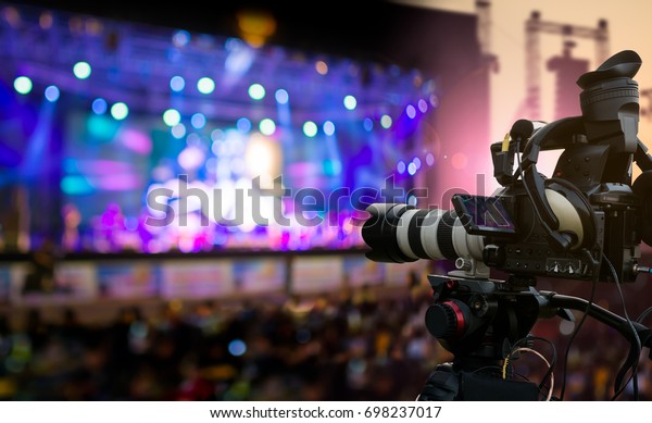 Video production covering event\
on stage by professional video camera in outdoor concert at\
sunset