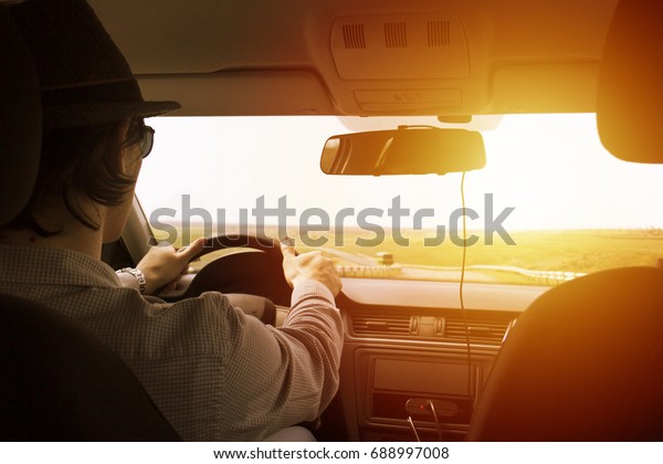 video recorder driving a car on highway. The\
hidden camera is hidden in the rear-view mirror The man in the hat\
drives the car. Sunset filter effect. Safety on the road. The road\
to success.