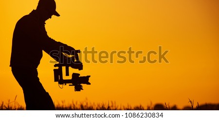 Video Stabilizer Operator. Taking Video Shoots Using DSLR Gimbal Equipment. Sunset Silhouette Concept.