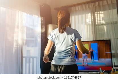 Video Streaming Stay Home.home Fitness Workout Class Live Streaming Online.Asian Woman Doing Strength Training Cardio Aerobic Dance Exercises Watching Videos On A Smart Tv In The Living Room At Home.