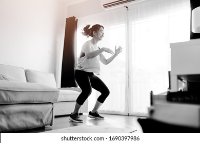 Video Streaming Stay Home.home Fitness Workout Class Live Streaming Online.Asian Woman Doing Strength Training Cardio Aerobic Dance Exercises Watching Videos In The Living Room At Home.Covid-19.