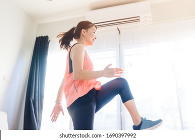 Video streaming Stay home.home fitness workout class live streaming online.Asian woman doing strength training cardio aerobic dance exercises watching videos in the living room at home.Covid-19.