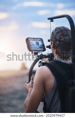 Videographer, back and man with video camera outdoor for professional production or creative film. Cameraman, record or shooting in nature with equipment for romantic movie of couple by car at sunset
