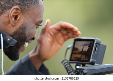 Videographer with black skin checking camera monitor after recording video