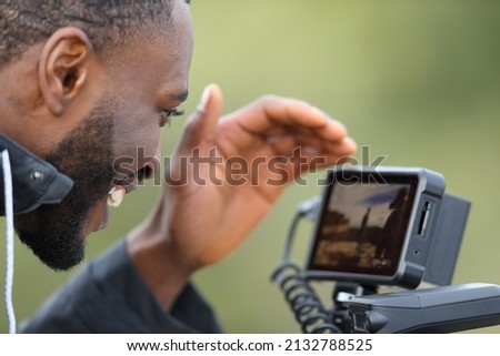 Videographer with black skin checking camera monitor after recording video