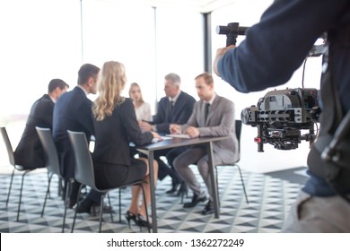 Videographer filming group of people at business meeting
