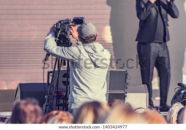 Videographer films with video camera by the stage\
at concert time.