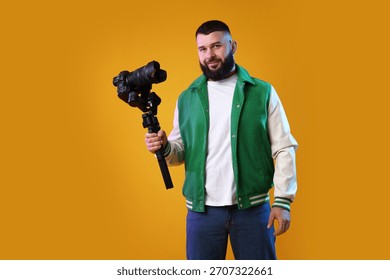 Videographer using gimbal stabilizer with camera on yellow background