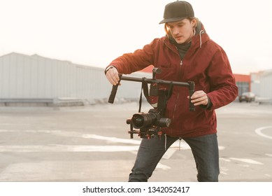 Videographer using steady cam. Cameraman creator with a stabilizer in his hands takes a video on the dslr camera at the background of the sunset. Creating a Video Concept.