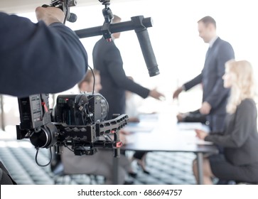 Videographer using steadycam, making video of business people shaking hands