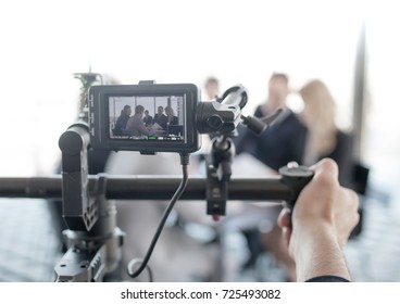 Videographer Using Steadycam, Making Video Of Business People At Meeting