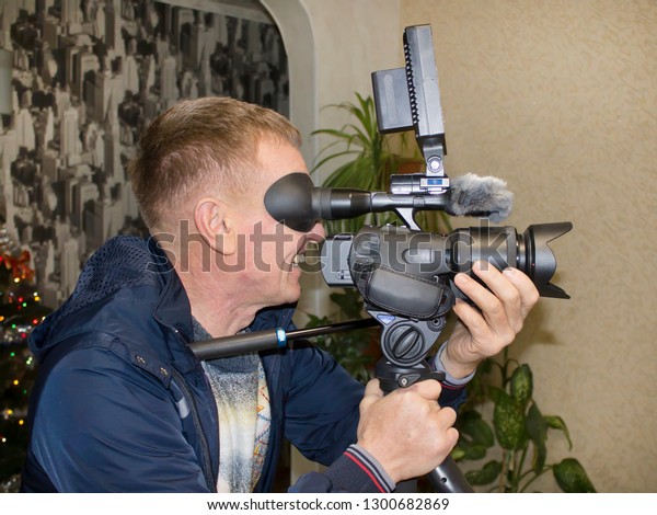 Videographer with a video camera in his hands\
shoots a holiday.