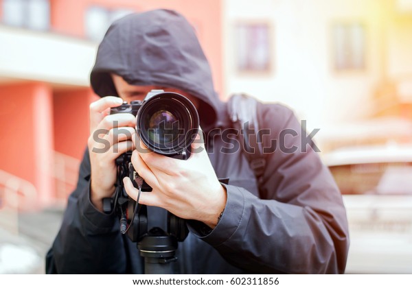 videographer is\
working. cameraman shooting of the plot. Blurred background. A man\
in a black jacket with a\
hood