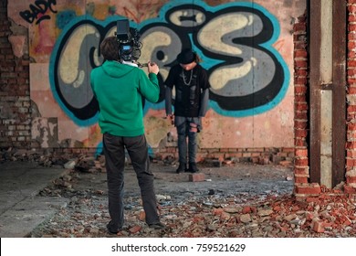 Videographer working with professional equipment video camera shooting clip in abandoned building. Model man posing near brick wall with graffity - Powered by Shutterstock - Get 15% off with code: PIKWIZARD15