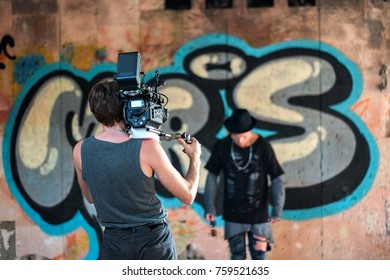 Videographer working with professional equipment video camera shooting clip in abandoned building. Model man posing near brick wall with graffity - Powered by Shutterstock