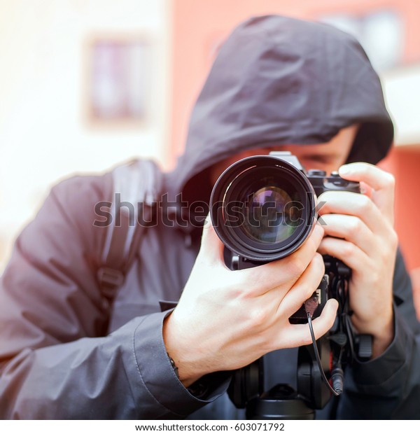 The videographer is\
working. Shooting of the plot. Blurred background. A man in a black\
jacket with a hood