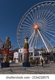 Vienna, Austria - 03-21-2022: Tourists Enjoying Their Time In Popular Amusement Park Wurstelprater Near Wiener Prater In Vienna, Austria With Tall Ferris Wheel Blumenrad On Sunny Day In Spring.