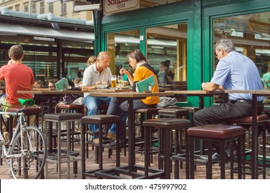 VIENNA, AUSTRIA - JUN 6: Dinner Of Busy People In Outdoor City Cafe With Tall Wooden Tables And Chairs On June 6, 2013. Vienna City Has Population Near 1.8 Million