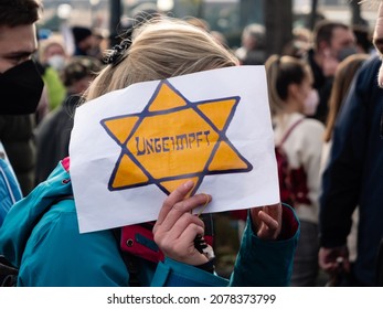 Vienna, Austria - November 20 2021: Anti-Vax Covid-19 Demonstrator Holding Sign 'Ungeimpft' or 'Unvaccinated' in a Yellow Patch or Jewish Badge Star of David.