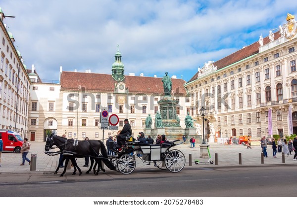 Vienna, Austria - October 2021:\
Horse carriage in Hofburg complex and Kaiser Franz I\
monument