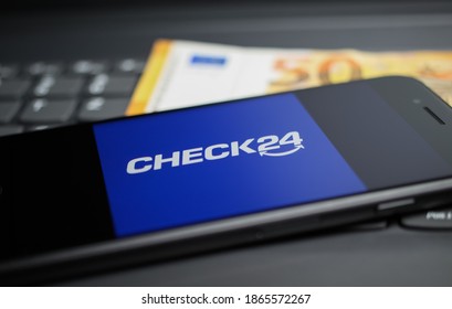 Viersen, Germany - April 9. 2020: Close up of mobile phone screen with logo lettering of Check24 comparison portal on computer keyboard, 50 Euro money background (selective focus on letter K)