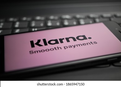 Viersen, Germany - April 9. 2020: Close up of mobile phone screen with logo lettering of Klarna payment provider on computer keyboard (selective focus on letter r)