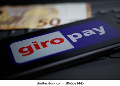 Viersen, Germany - April 9. 2020: Close up of mobile phone screen with logo lettering of giropay payment provider on computer keyboard (selective focus on upper part of letter O)