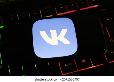 Viersen, Germany - December 9. 2021: Cloesup of mobile phone screen with logo lettering of vk messenger service on computer keyboard (focus on center of white logo)