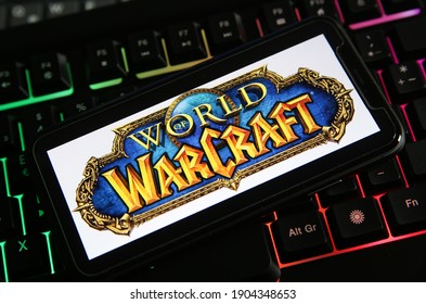 Viersen, Germany - January 9. 2021: Closeup of smartphone screen with logo lettering of online game world of warcraft on illuminated computer keyboard (focus on center of lettering)