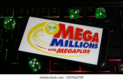 Viersen, Germany - March 1. 2021: Closeup of smartphone with logo letterin of american megamillions lottery game on computer keyboard (focus on red upper letter M)