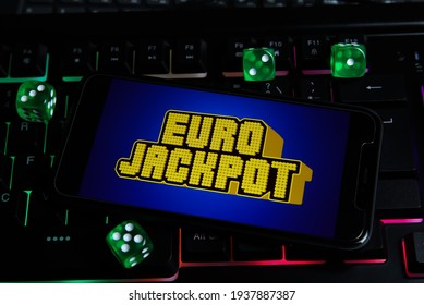 Viersen, Germany - March 1. 2021: Closeup of smartphone with logo letterin of euro jackpot  lottery game on computer keyboard (focus on center of upper lettering)