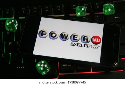 Viersen, Germany - March 1. 2021: Closeup of smartphone with logo letterin of american powerball powerplay lottery game on computer keyboard (focus on center of upper lettering)