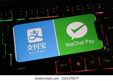 Viersen, Germany - March 9. 2022: Closeup of mobile phone screen with logos of chinese alipay and wechat together on computer keyboard 