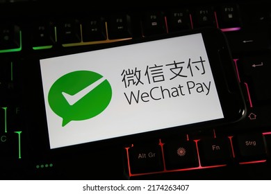 Viersen, Germany - March 9. 2022: Closeup of mobile phone screen with logo lettering of wechat pay on computer keyboard (focus on center of upper lettering)