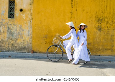 Vietnam girls with a vietnamese traditional costume wearing Ao dai ride a bicycle at Hua. Many vietnam woman in hue city still wearing traditional dress.Hue is old town and many history building