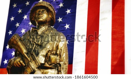 A Vietnam memorial statue with the American flag in the background.