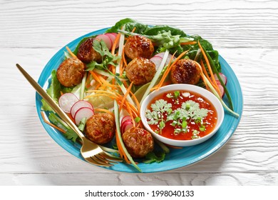 Vietnamese Banh Mi Salad With Pork Meatballs, Carrot, Cucumber, And Radish Served Over Romaine Lettuce Salad On A Blue Plate With Sweet Chili Sauce On White Wooden Background, Top View, Close-up