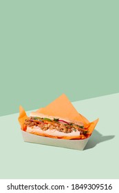 Vietnamese Banh Mi Sandwich With Roasted Cauliflower And Pickled Veggie In Takeaway Packaging Box On Green Background With Copy Space.Restaurant Food Delivery Concept