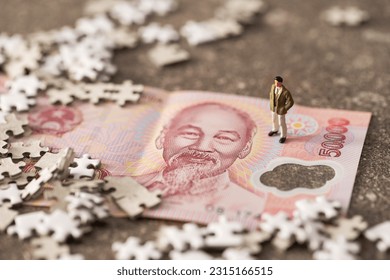 Vietnamese banknotes, jigsaw puzzles, and businessman miniatures - Shutterstock ID 2315166515